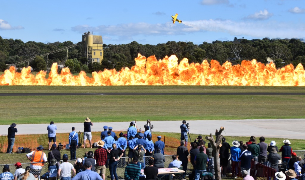 A Paul Bennet Pitts Special flies over a pyrotechnic display